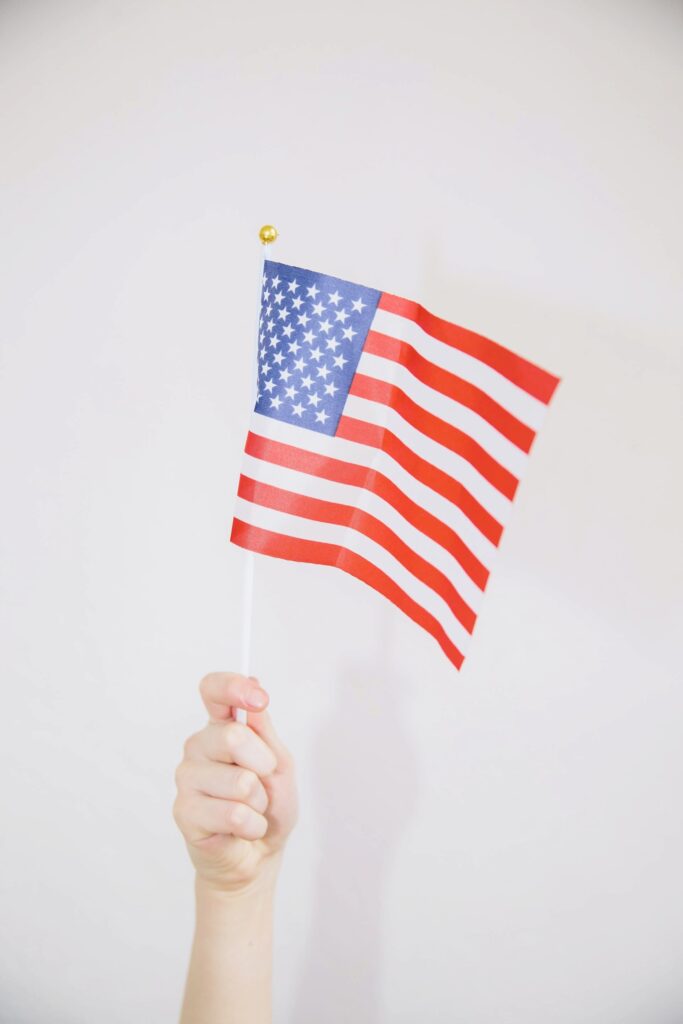 A child's hand holding an american flag against a white background.
