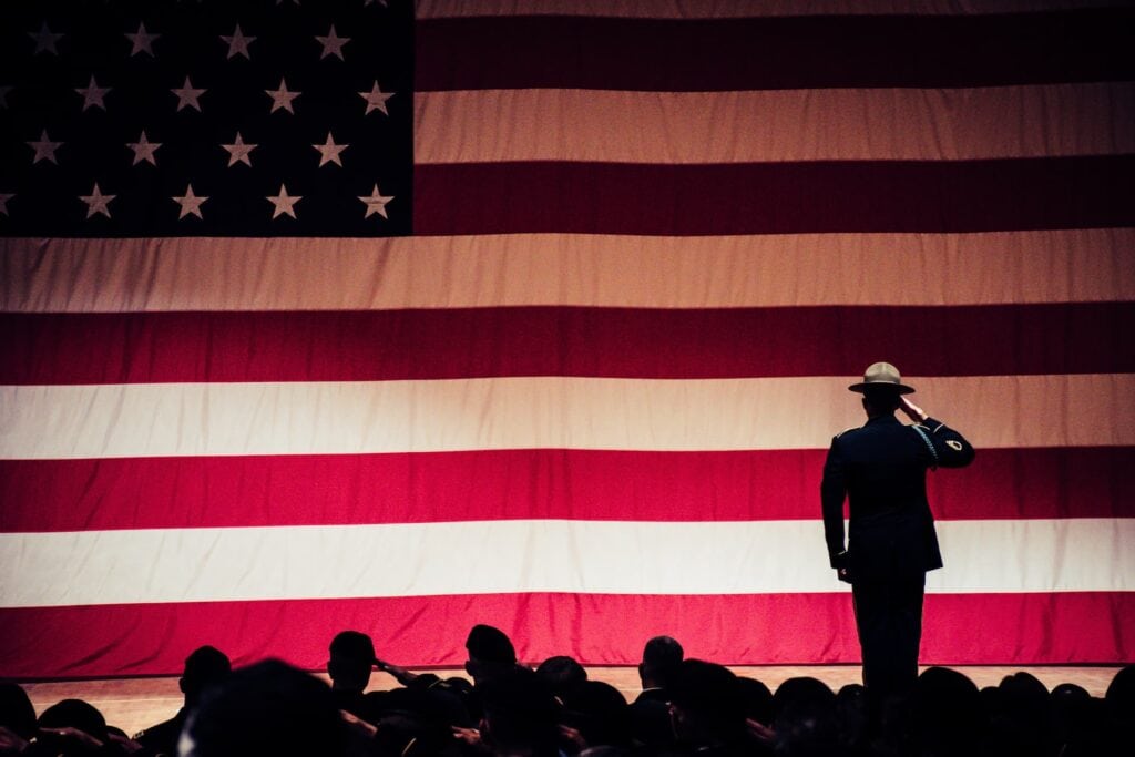 A man is standing in front of an american flag.